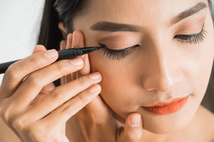 A makeup artist applying graphic liner to create a winter makeup look