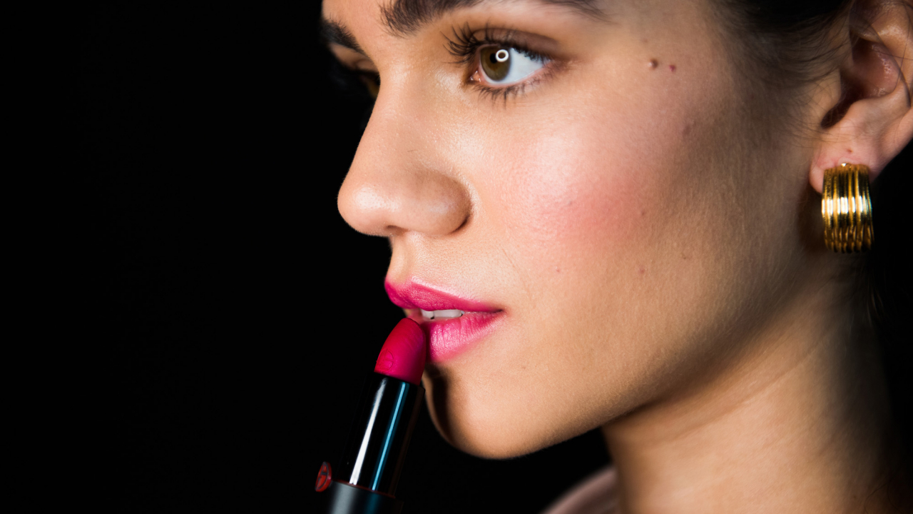 A makeup artist applying brick lipstick to create a winter makeup look